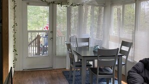 Een eethoek met een tafel, stoelen, een schuifpui en uitzicht op de omgeving.