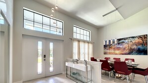 A modern kitchen with a central island, large windows, and a dining area with red chairs. -  New Exceptional  Villa Hidden Pearl - Has It All! (Cape Coral)