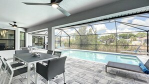 An outdoor pool area with a dining table and chairs, a ceiling fan, and a view of the surrounding neighborhood. -  New Exceptional  Villa Hidden Pearl - Has It All! (Cape Coral)