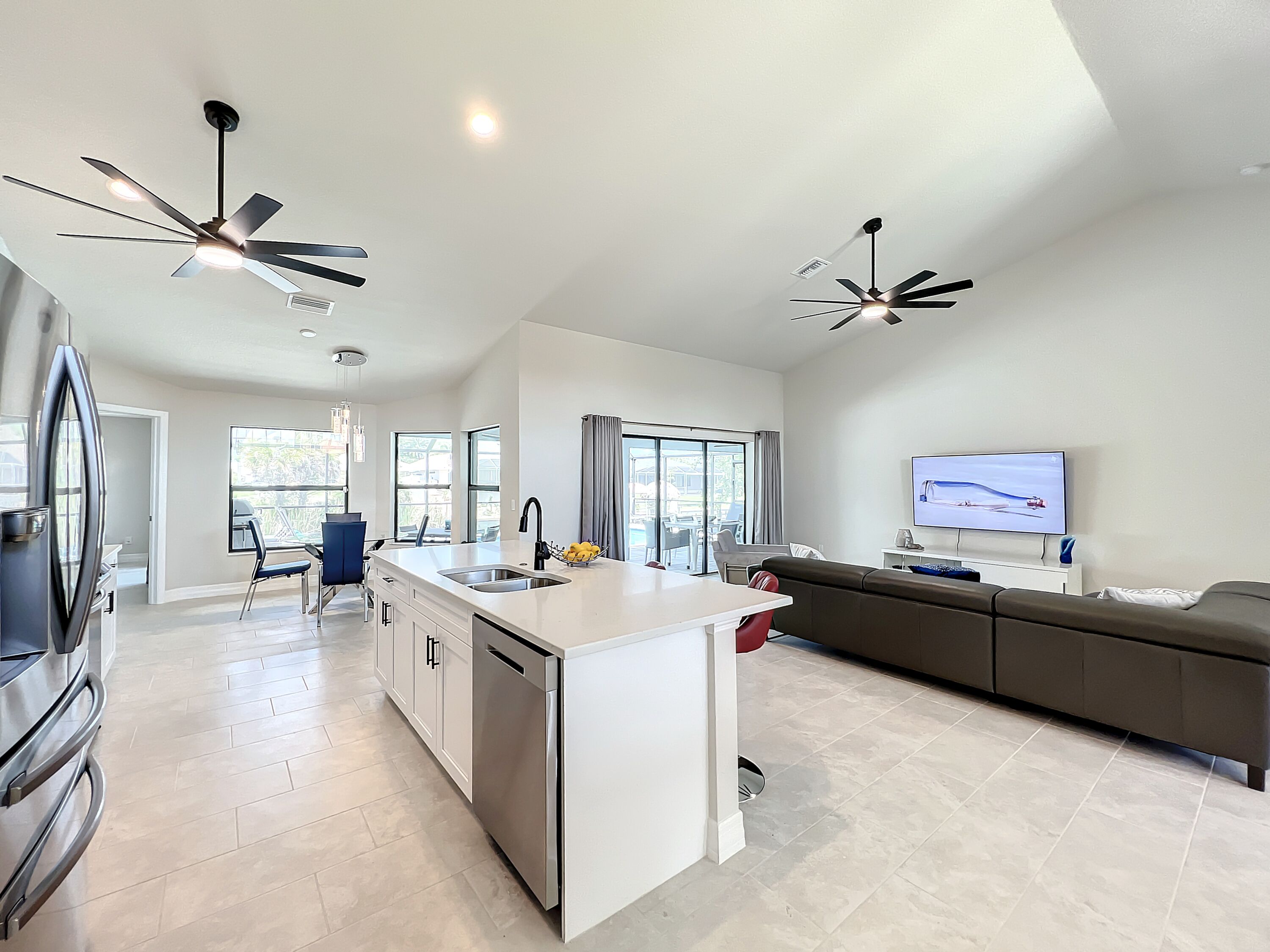 Una cocina moderna con una isla central, electrodomésticos de acero inoxidable y un comedor con una silla azul.