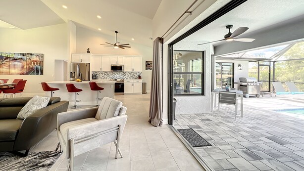A spacious living area with a modern kitchen, a dining area, and a patio with a pool. -  New Exceptional  Villa Hidden Pearl - Has It All! (Cape Coral)