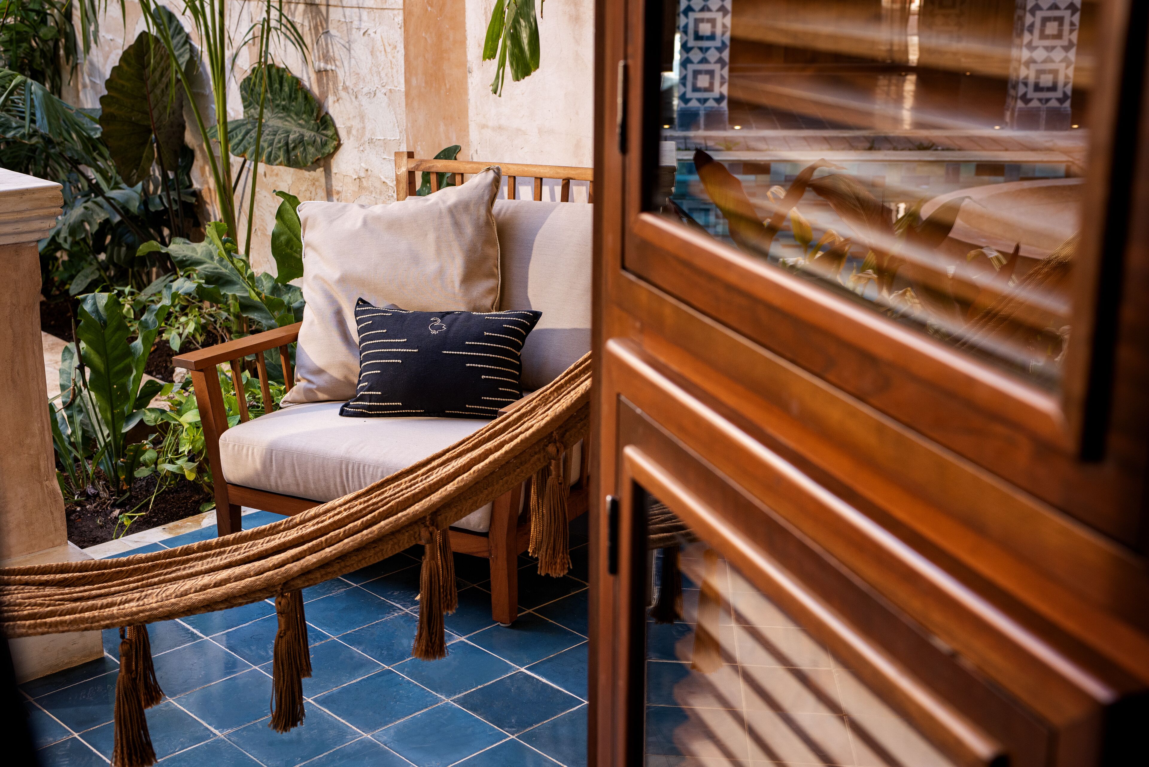 A hammock chair with cushions, a wooden cabinet, and a tiled floor.