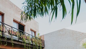 Un espace aménagé au bord de la piscine avec des sièges disposés en cercle, une terrasse couverte avec des meubles d’extérieur et un mur en pierre.