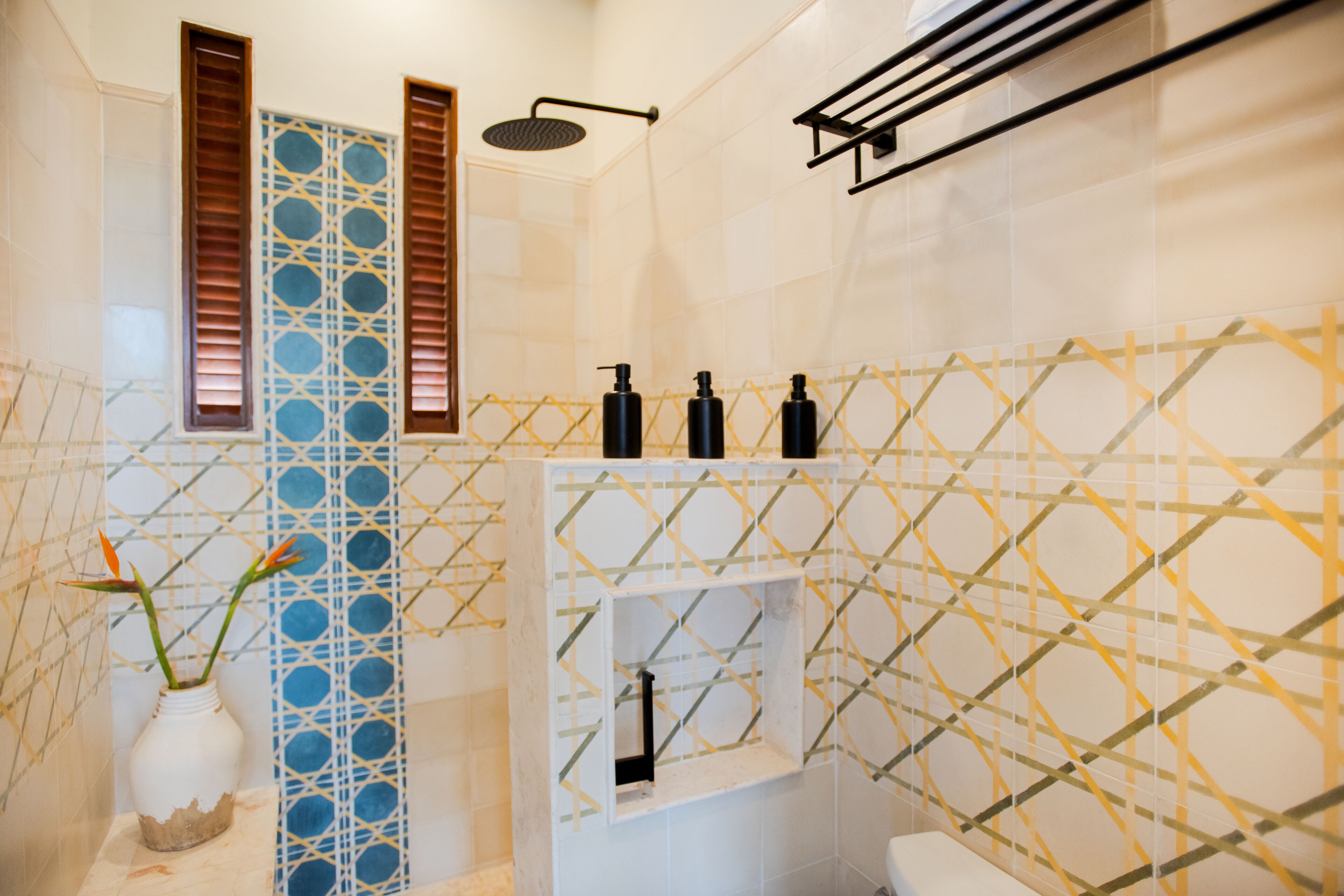 A bathroom with a shower, toilet, and a shelf with toiletries.