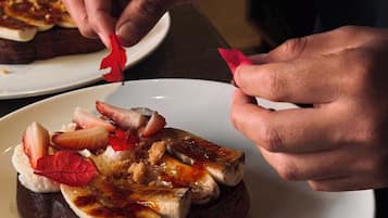 Hands placing a strawberry on a dessert.