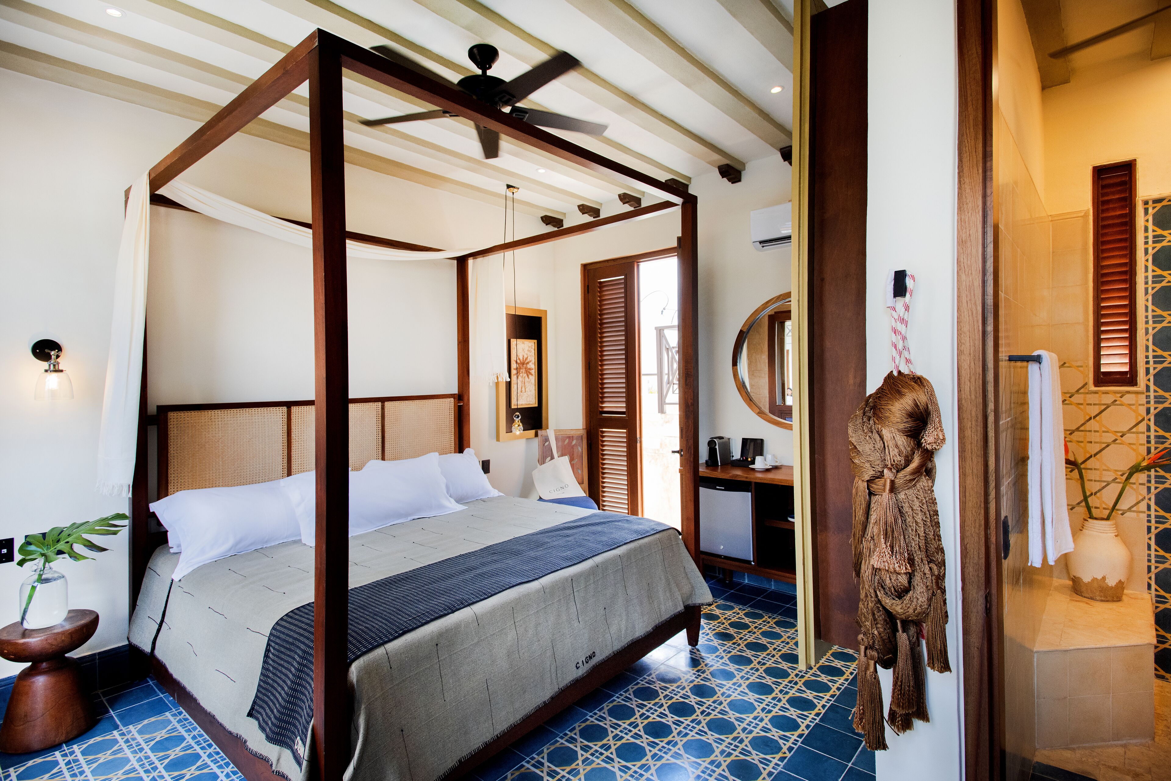 A four-poster bed with a wooden frame, a bedside table, and a mirror.