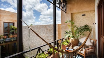 A balcony with a hammock, potted plants, and a view of the sky.