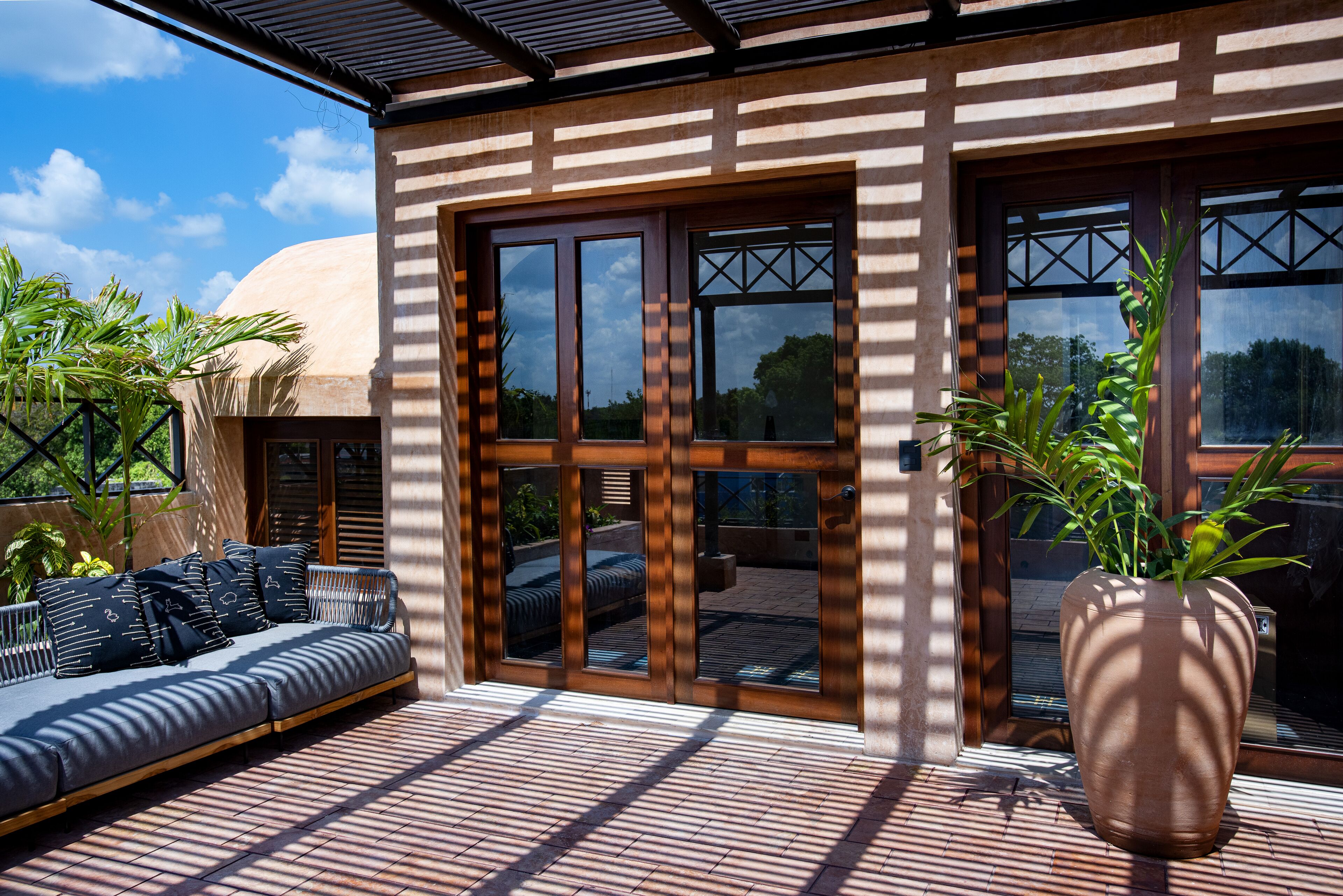 A modern outdoor seating area with a sofa and a large planter.