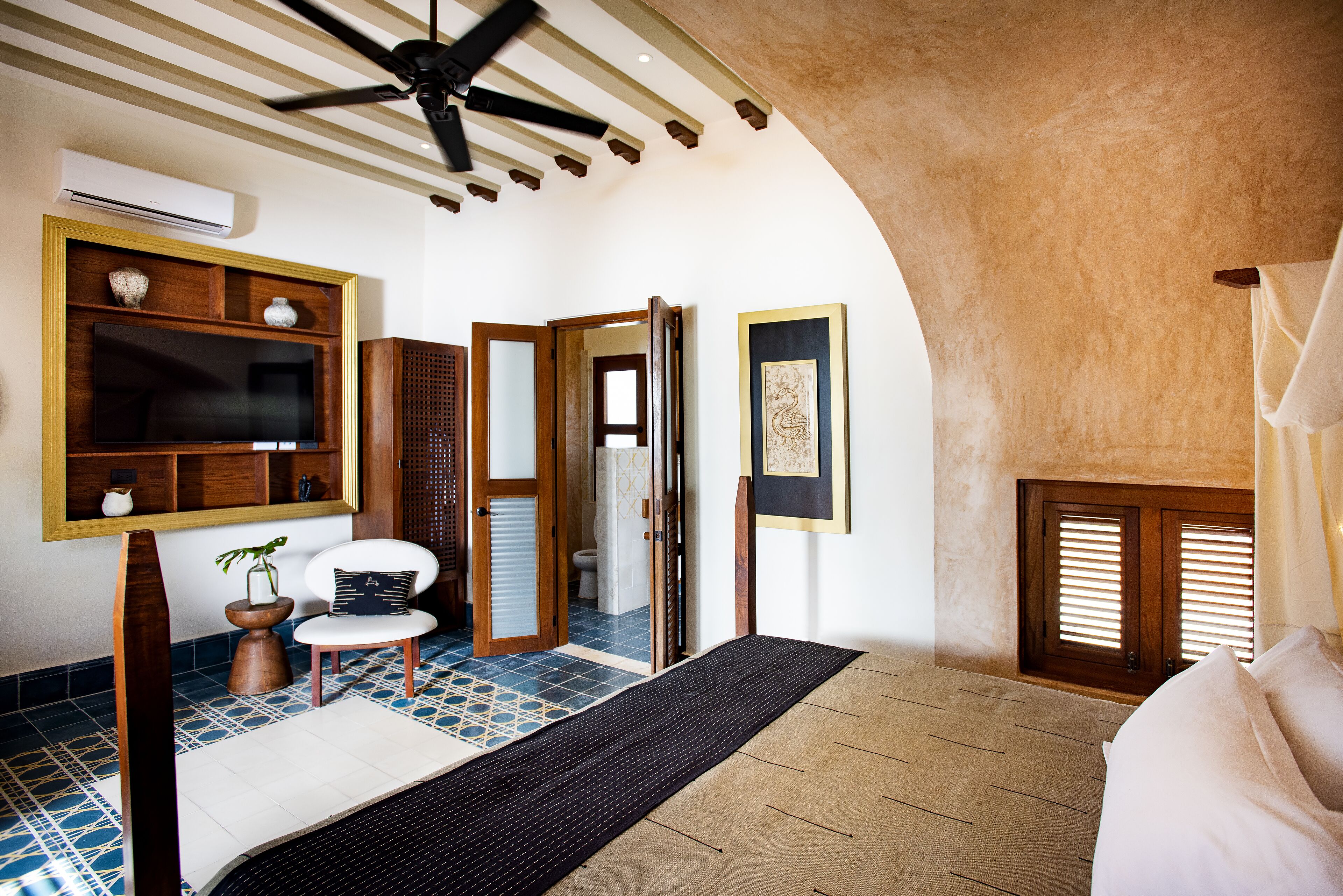 A traditional Japanese-style room with tatami flooring, a ceiling fan, a television, and a sliding door leading to a bathroom.