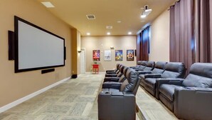 Une salle de cinéma privée dotée d’un grand écran, de fauteuils en cuir inclinables et d’un sol recouvert de moquette.