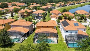 Un quartier résidentiel avec des maisons aux toits recouverts de tuiles rouges, une piscine et une rivière en arrière-plan.