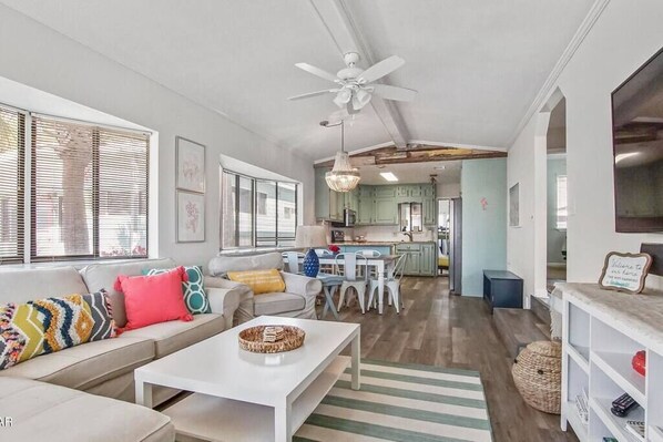 A modern living room with a sofa, coffee table, and dining area. - House for 6 - Golf Cart (street legal), pvt beach (Lower Grand Lagoon)