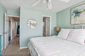 A bedroom with a bed, a ceiling fan, a round mirror, and a painting on the wall. - House for 6 - Golf Cart (street legal), pvt beach (Lower Grand Lagoon)