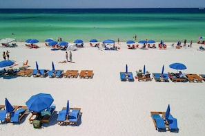 A beach with rows of sun loungers and umbrellas, a clear blue sea, and a few people in the distance. - House for 6 - Golf Cart (street legal), pvt beach (Lower Grand Lagoon)
