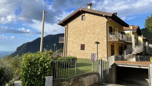 Ein Steinhaus mit Balkon, einem verschlossenen Eingang und einer Bergkulisse.