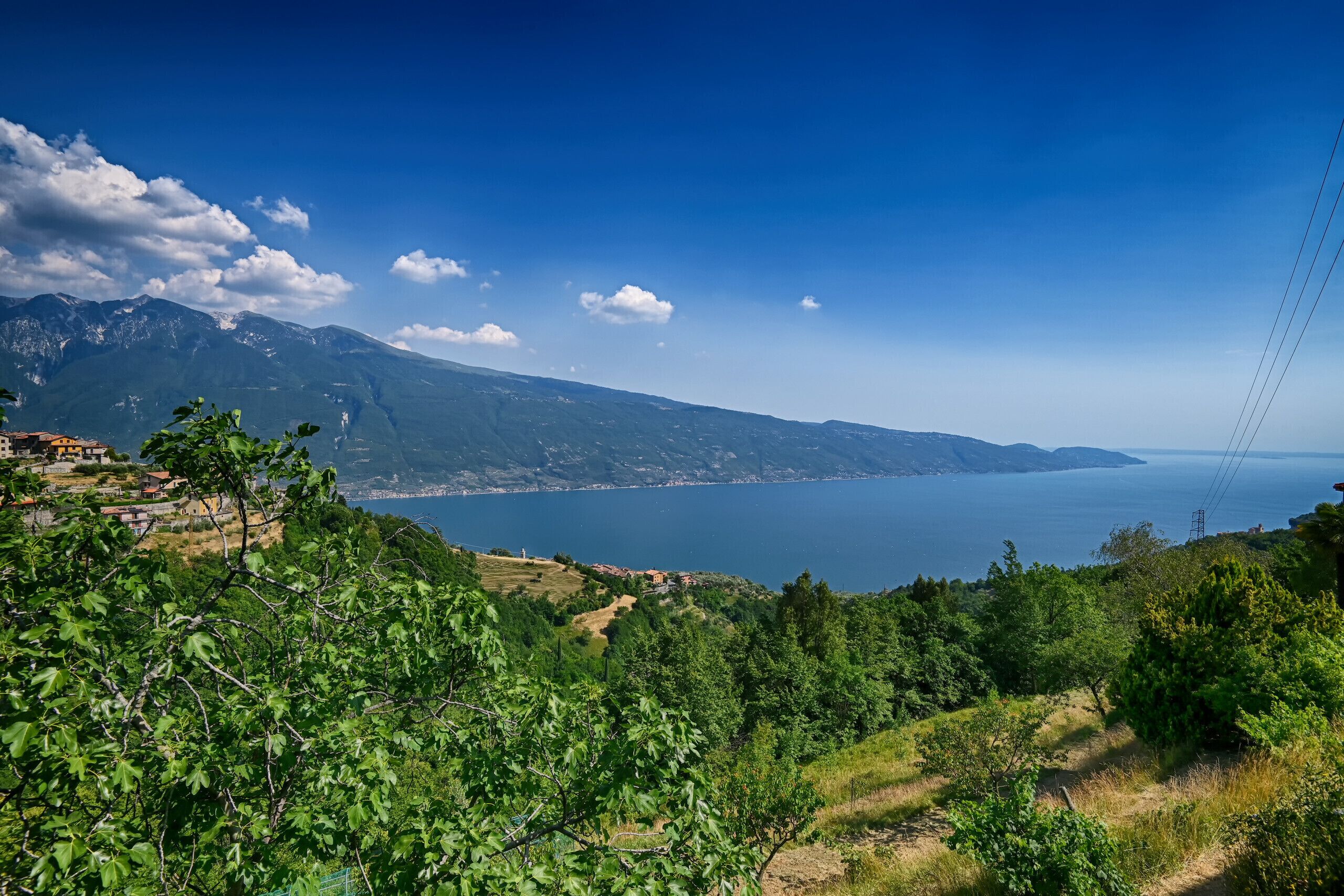 Paesaggio costiero con montagne, cielo sereno e vista sul mare.