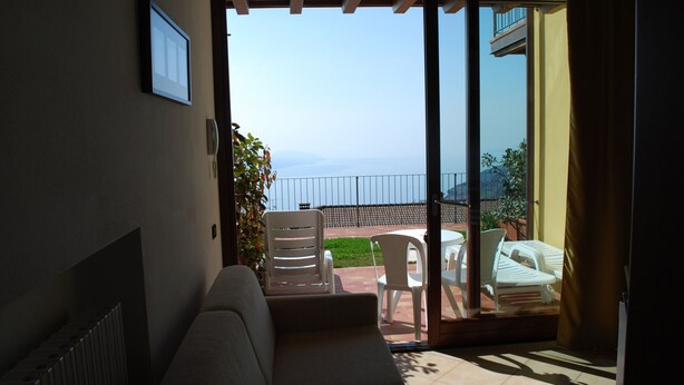 A balcony with a sofa, chairs, and a view of the sea.