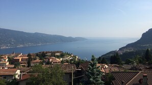 A coastal town with terracotta-roofed buildings, a clear blue sea, and hilly terrain in the background. - Francesco by Theater Home, with pool and marvellous lake view (Tignale)