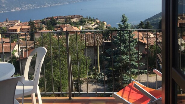 A balcony with a view of the sea, a chair, and a table. - Francesco by Theater Home, with pool and marvellous lake view (Tignale)