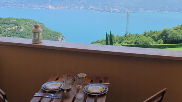 A balcony with a table set for two, overlooking a lake and mountains. - Nadia by Theater Home, with garden and marvellous lake view (Tignale)