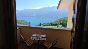 A balcony with a table set for two, overlooking a lake and mountains. - Nadia by Theater Home, with garden and marvellous lake view (Tignale)