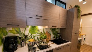 Una cocina moderna con armarios de madera, estufa a gas, cafetera y lavadora al fondo.