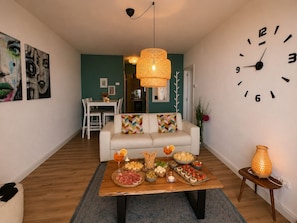 A living room with a wooden coffee table, a sofa, a dining table, and a wall clock. - Elisa by Theater Home, with big terrace and marvellous lake view (Tignale)