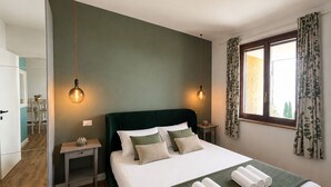 Un dormitorio con cama, dos mesitas de noche, un espejo y una ventana con cortinas.