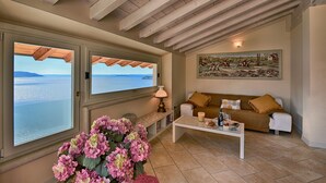 Un salon avec vue sur la mer, un canapé, une table basse et un tableau accroché au mur.