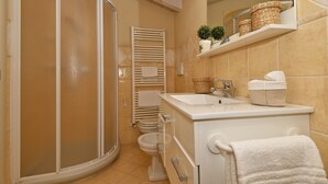 Une salle de bain équipée d’une douche, de toilettes, d’un lavabo et d’un porte-serviettes.