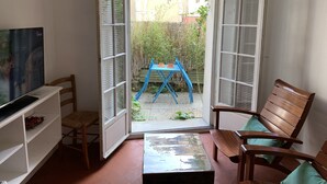 A small room with a television, a wooden chair, a blue table, and a bench. - Duplex apartment (two people) (Dieppe)