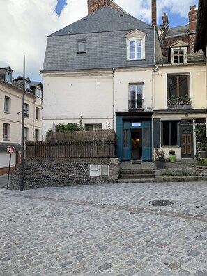 Eine Kopfsteinpflasterstraße mit einem Gebäude, das eine blaue Tür und einen kleinen Balkon mit Topfpflanzen hat.