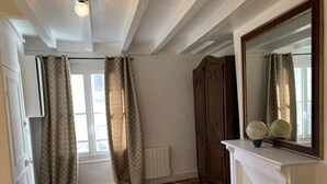 A room with wooden flooring, a white radiator, a large mirror with globes, and a wardrobe. - Duplex apartment (two people) (Dieppe)
