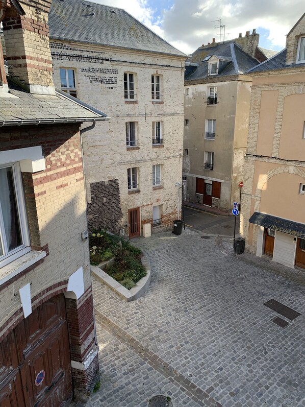 A cobblestone courtyard surrounded by historic buildings with multiple windows and doors.