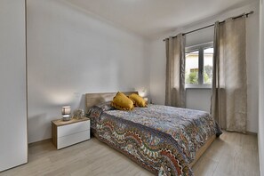 Relax in a serene bedroom with a neatly made bed, bedside table, and window with a view.