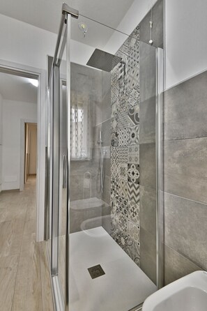 Enjoy a refreshing shower or soak in the spacious bathtub, surrounded by geometric and floral tile patterns.