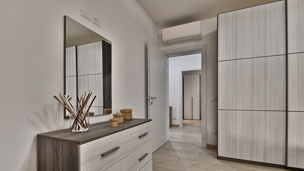 Un couloir moderne avec une commode en bois, un miroir et des paniers en osier.
