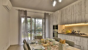 Une cuisine moderne avec un coin repas, de grandes fenêtres et une vue sur l’extérieur.