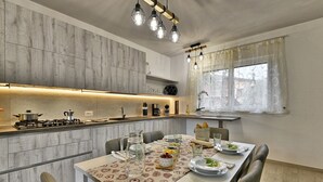 Une cuisine moderne dotée d’un îlot central, d’une table à manger dressée avec des assiettes et des verres, et d’un éclairage suspendu au-dessus.