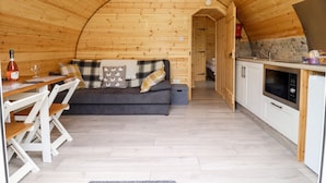 A cozy wooden cabin interior with a dining area, sofa, and kitchen. - Meadow Lodge @ Berrys Place Farm (Gloucester)