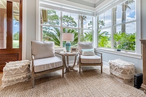 Relax in a cozy seating area with two chairs and a small table, surrounded by lush greenery views.