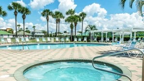 A swimming pool with a tiled deck, lounge chairs, and palm trees in the background. - NEW! Newly updated 2 bedroom 2 bath condo - 2 minute walk to beach. (Miramar Beach)