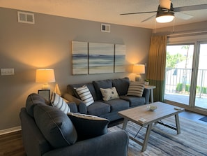 A living room with two grey sofas, a wooden coffee table, and a ceiling fan.