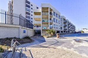 Um edifício residencial com várias andares, varandas, portão fechado e céu claro.