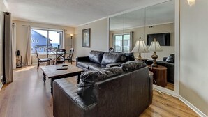 Un salon moderne avec un canapé en cuir, une table à manger et un grand miroir.