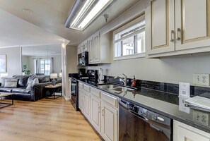 Una cocina moderna con armarios blancos, encimera negra y lavavajillas integrado.