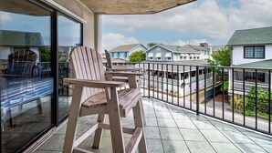 Un balcon avec des chaises en bois et une porte vitrée donnant sur un espace patio.