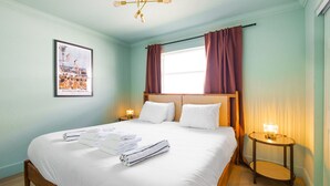 A hotel room with a large bed, two bedside tables with lamps, a framed picture on the wall, and a window with curtains. - 137 · ☀Pool✔ Kitchen✔ Beach✔ Self Checkin✔ Free Parking✔ (Clearwater)