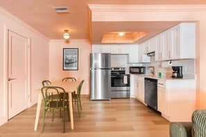A modern kitchen with white cabinets, stainless steel appliances, and a dining area with a table and chairs. - 137 · ☀Pool✔ Kitchen✔ Beach✔ Self Checkin✔ Free Parking✔ (Clearwater)