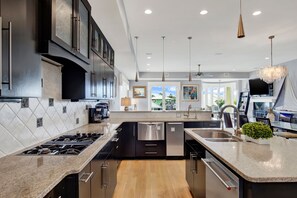 A modern kitchen with a central island, stainless steel appliances, and a view to the living area.